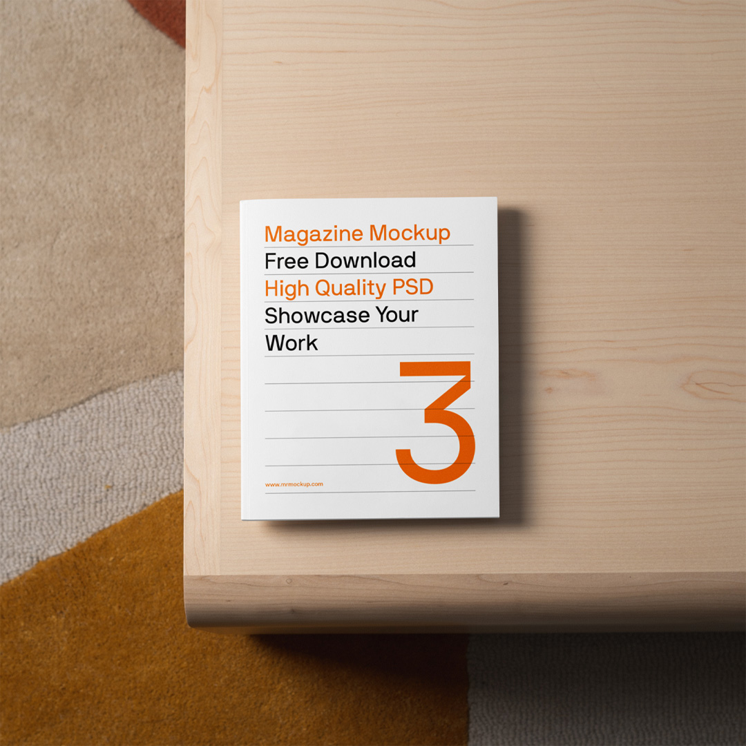 A magazine mockup laying on a bright wood table is seen from above.